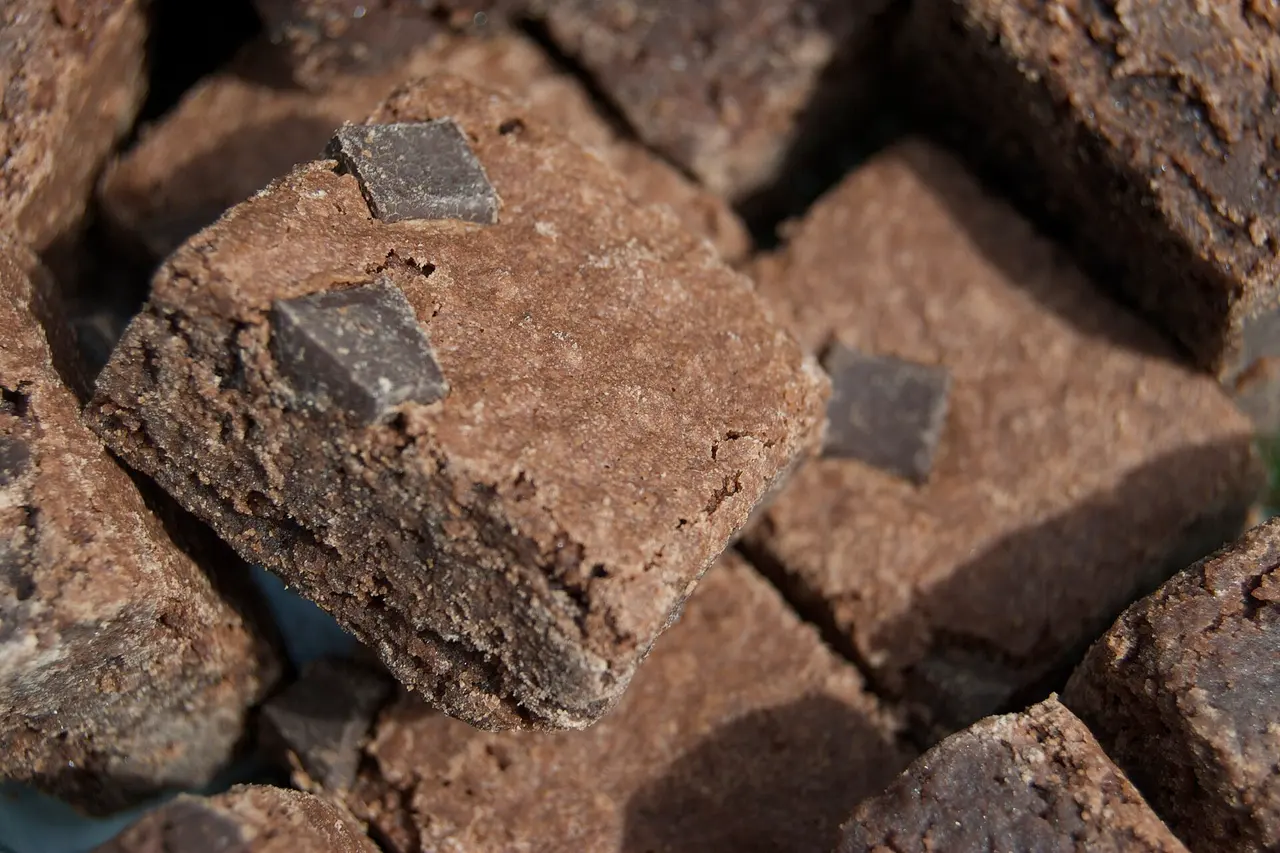 Pedaços de brownie com lascas de chocolate amargo por cima, empilhados de perto.